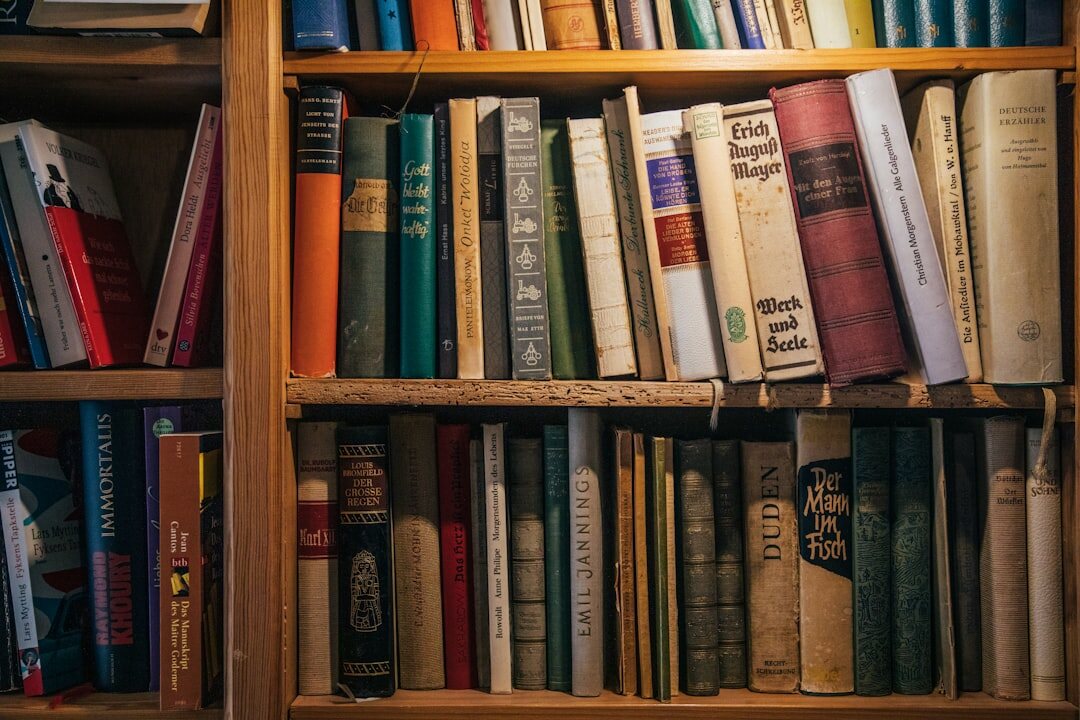 Old wooden bookshelf filled with worn hardcover books in warm light