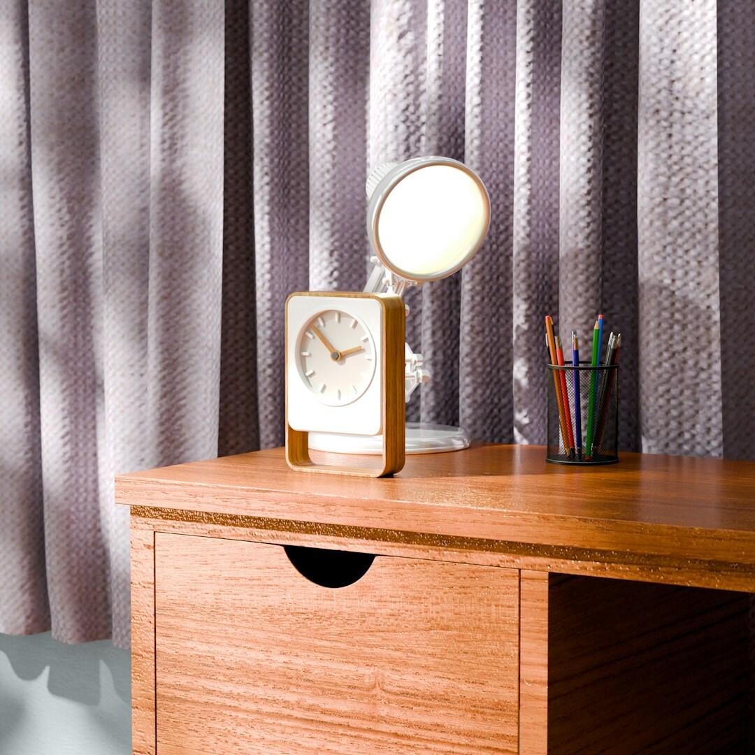 Hand writing notes in a notebook at a wooden desk lit by a lamp